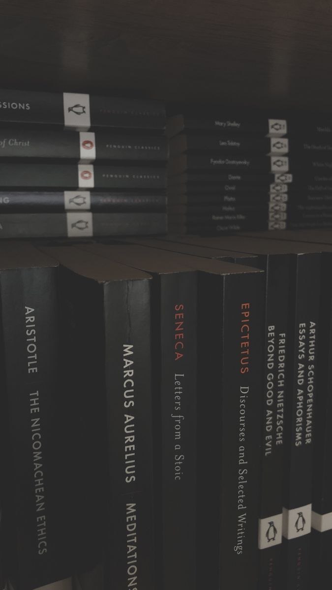 a row of black books sitting on top of a wooden book shelf next to each other