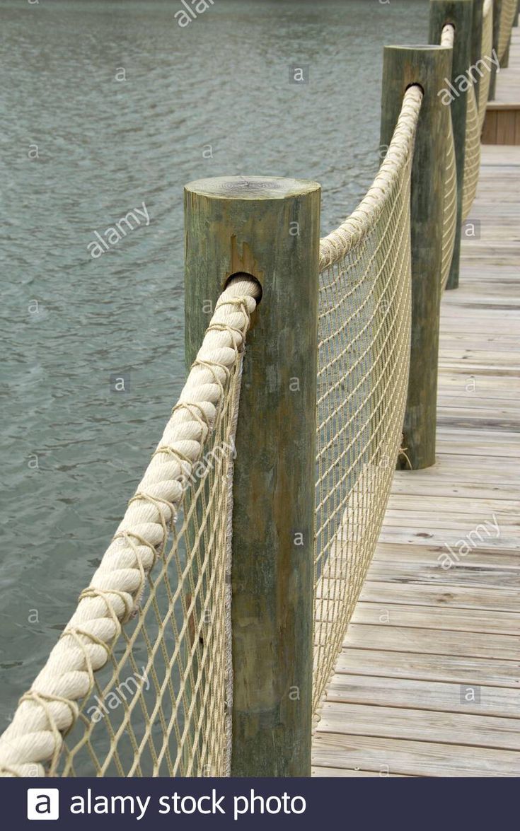 a roped bridge over the water with boats in the backgrounnds