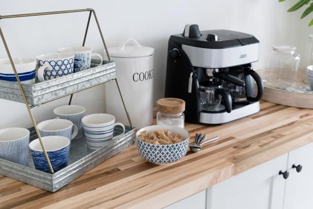 a coffee maker and cups are sitting on a kitchen counter with other items in front of it