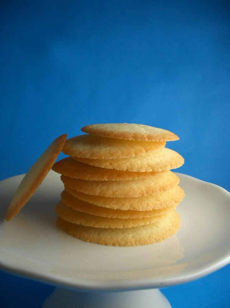 a stack of cookies sitting on top of a white plate next to a blue background