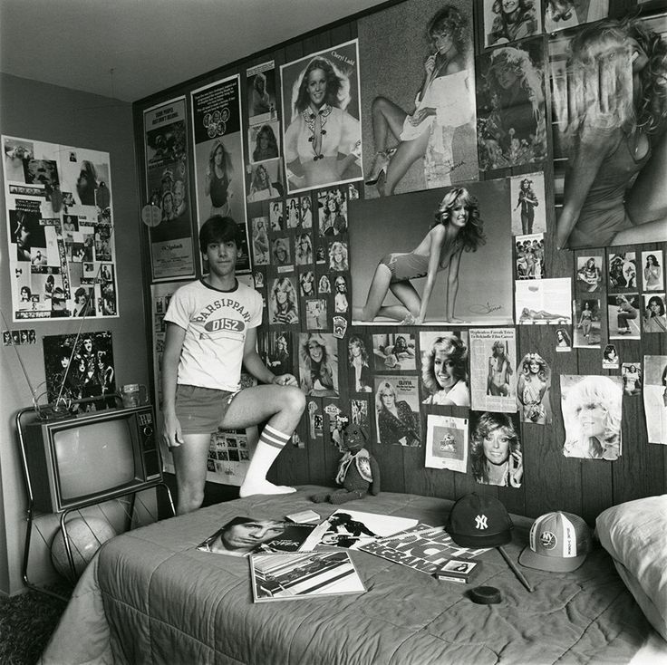 a man standing in front of a bed covered with pictures and posters on the wall