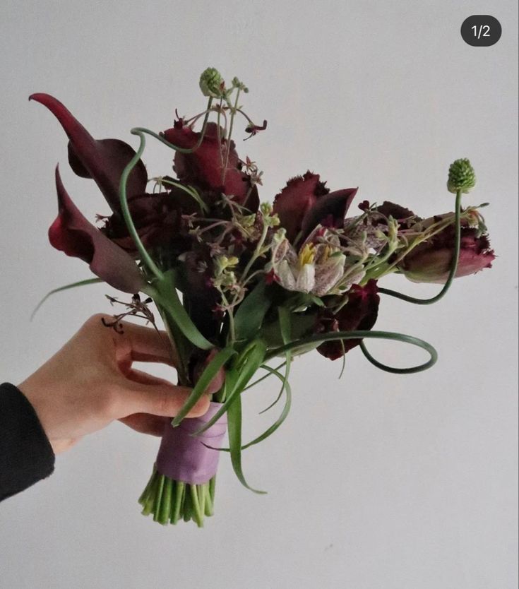 a person holding a bouquet of flowers in their left hand and the other hand with it