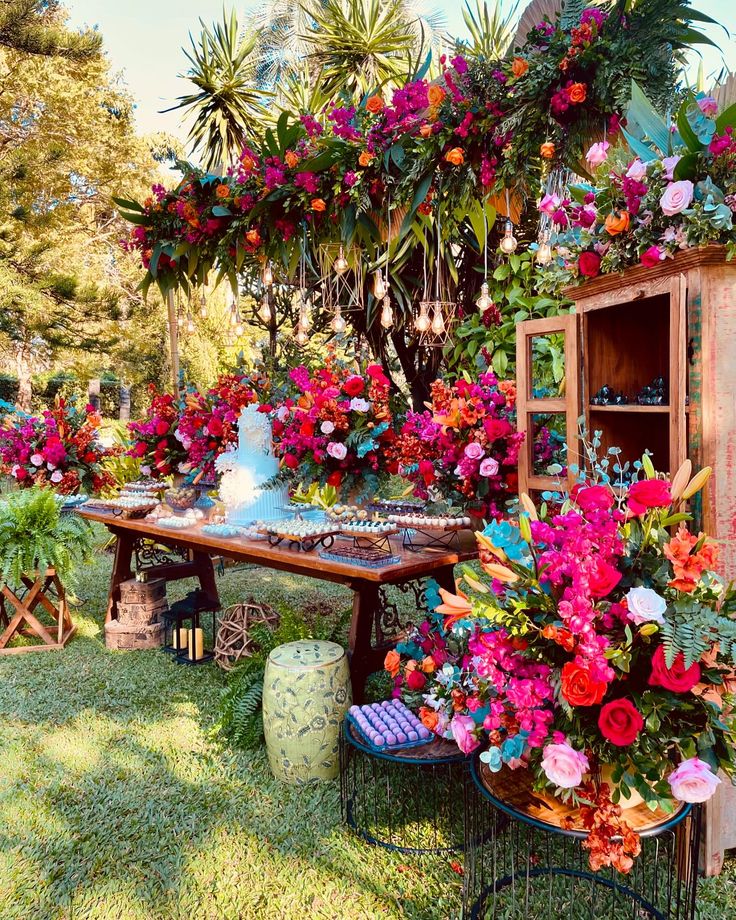 a table with flowers on it in the middle of some grass and plants around it