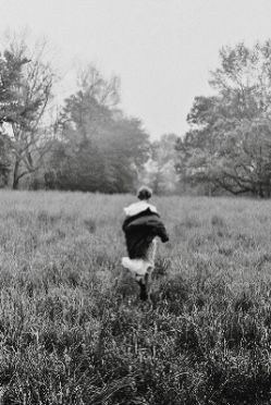 black and white photograph of a person running through a field