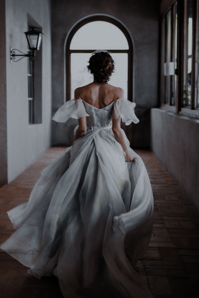 a woman in a white dress is walking down the hall with her back to the camera