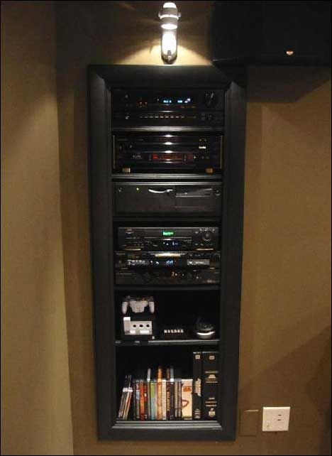 an entertainment center in the corner of a room with remotes and books on it