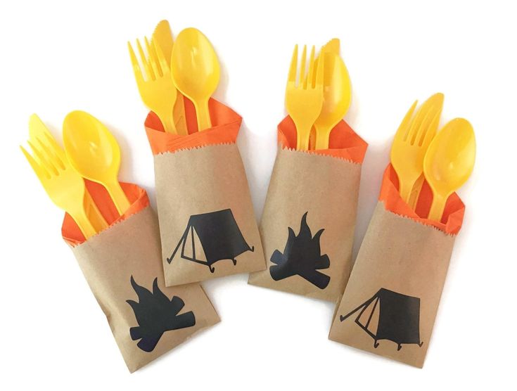 three bags with forks and spoons in them on a white surface, one has a camping theme