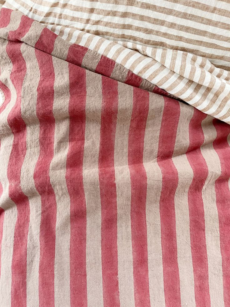 an unmade bed with red and white striped sheets