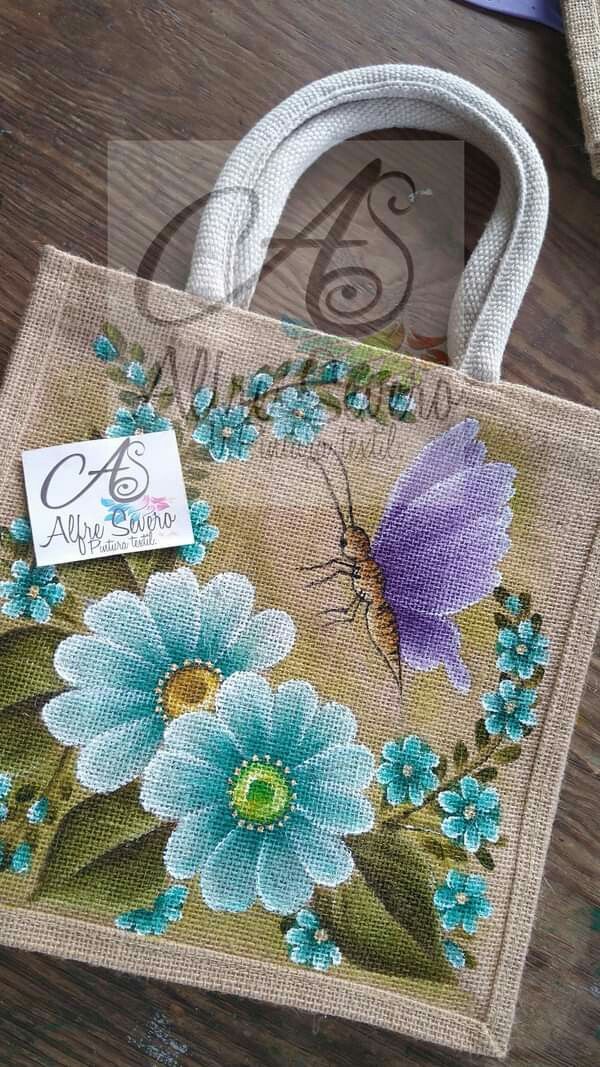 a bag with flowers painted on it sitting on top of a wooden table next to scissors