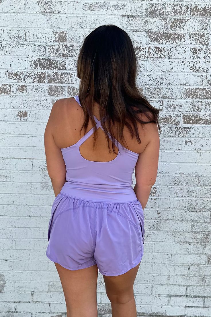 This Athletic Cut Out Romper in Lavedner offers a winning combination of style and comfort. It's made from a soft blend of nylon and spandex, so you can be agile without sacrificing on fashion. Perfect for casual days and athleisure, the criss cross straps and small cut-out under the chest make sure you're turning heads - in all the right ways. Get fit in style! Model is wearing a size large. Stocked at Arlington Village and Uptown. Solid Nylon Activewear With 4-way Stretch, Summer Activewear With Built-in Bra And High Stretch, Nylon Activewear With Built-in Bra, 4-way Stretch Nylon Activewear For Light Exercise, Nylon Activewear For Light Exercise With 4-way Stretch, Versatile Nylon Activewear With Built-in Shorts, Versatile Sleeveless Nylon Activewear, Purple Nylon Activewear For Workout, Purple Nylon Activewear For Gym