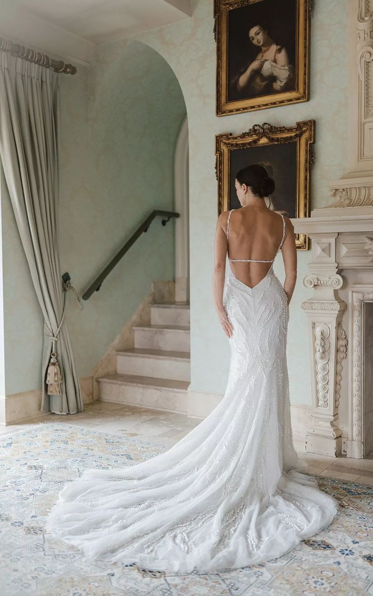 a woman in a white wedding dress looking at the stairs and painting on the wall