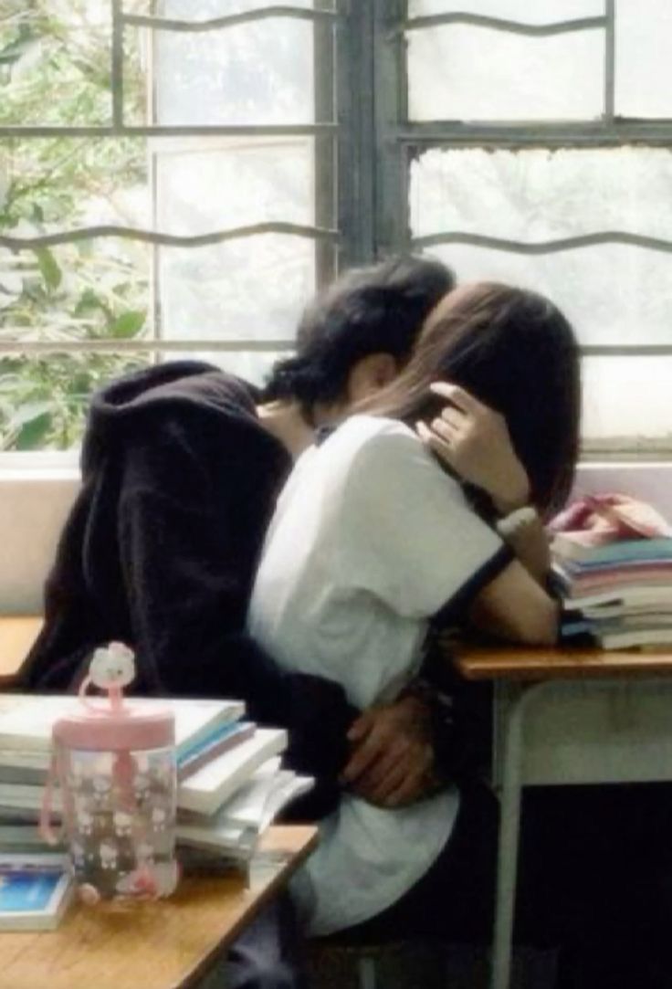 two people hugging each other in front of a table with books and drinks on it