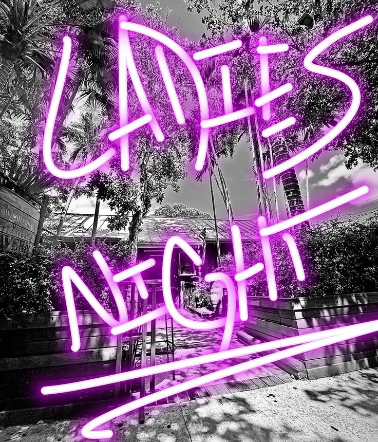 a neon sign that says ladies night in front of some trees and bushes with palm trees behind it