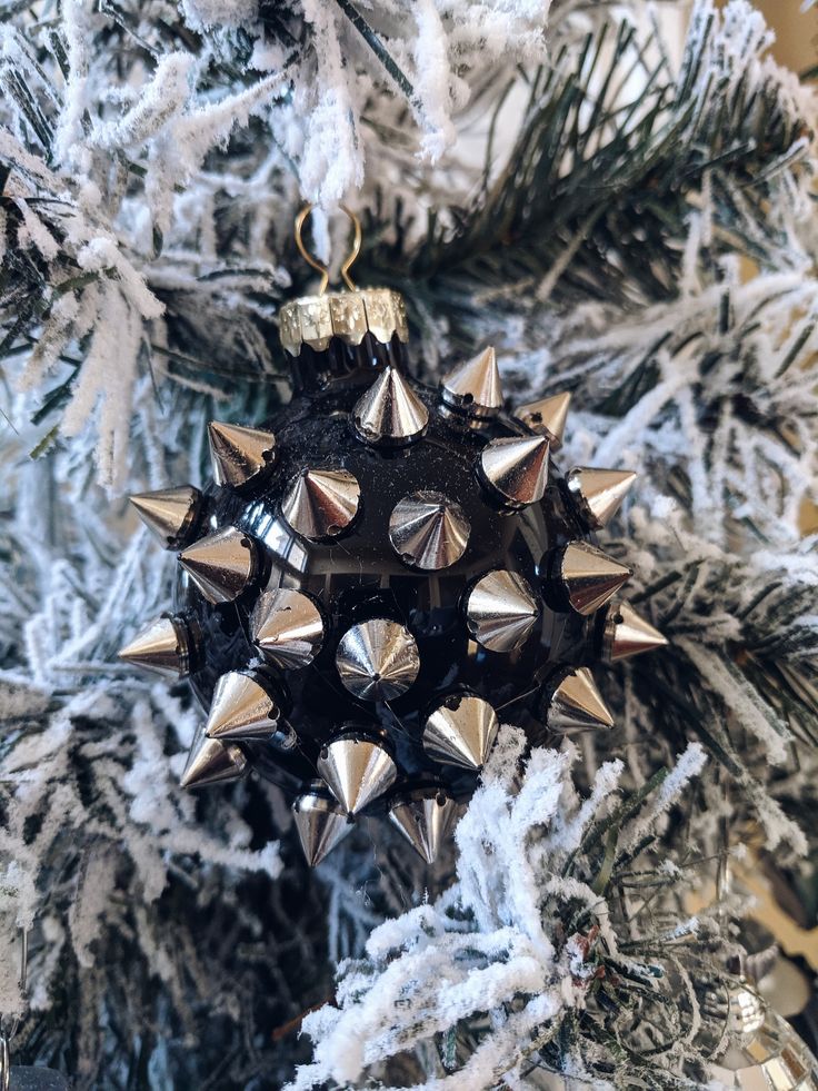 a christmas ornament hanging from the side of a tree with snow on it