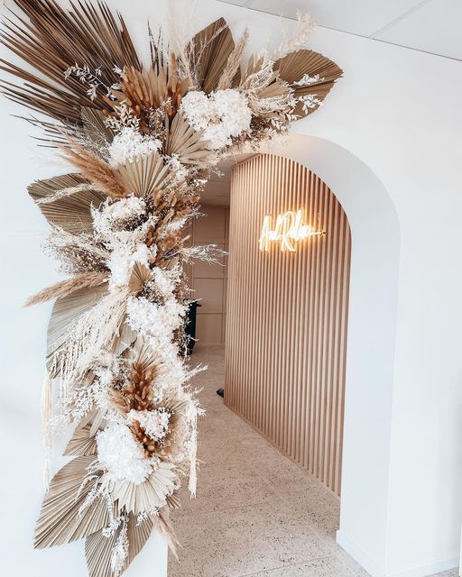 a room with white walls and a large mirror on the wall that has dried flowers hanging from it