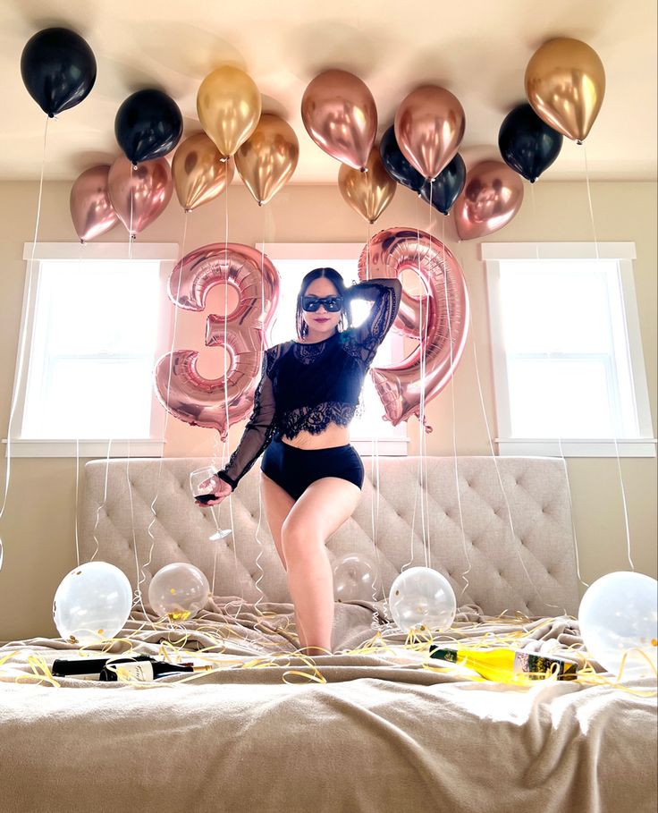 a woman standing on top of a bed next to balloons