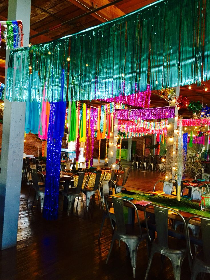 an empty restaurant with tables and chairs covered in colorful curtains hanging from the ceiling,