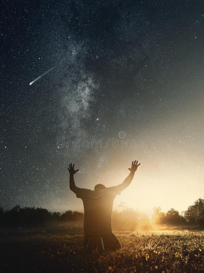 a man standing in the grass with his arms up and hands raised to the sky