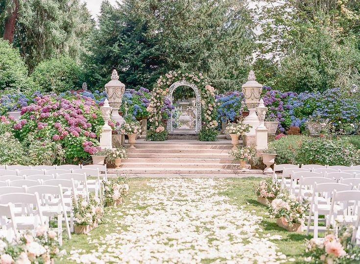 an outdoor ceremony setup with white chairs and flowers