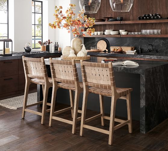 a kitchen with wooden floors and black counter tops next to a dining room table filled with chairs