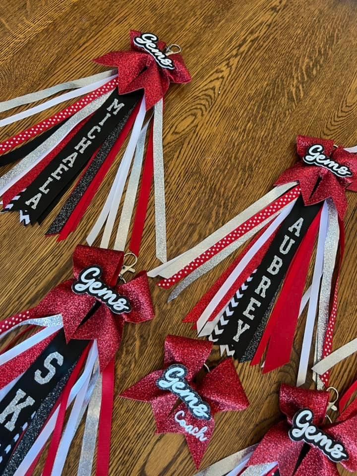 red, white and black ribbons with the words happy birthday hanging from them on a wooden table