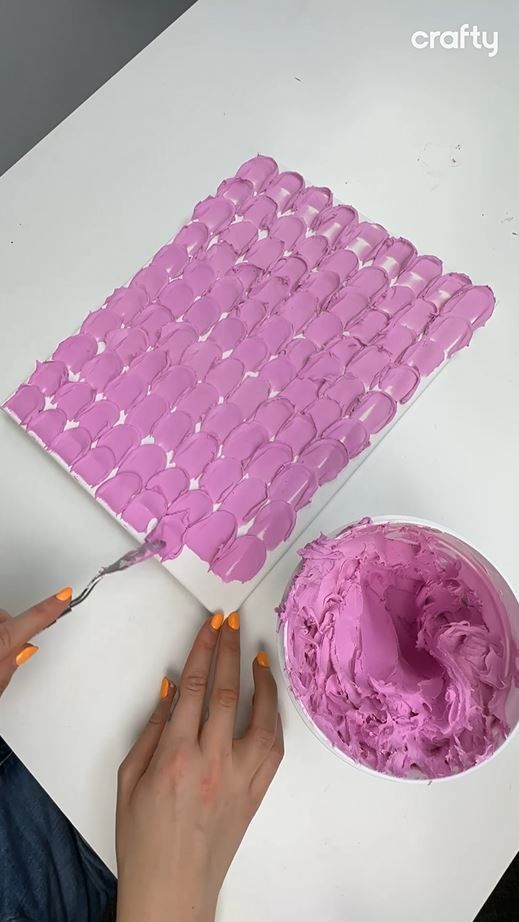 a woman is painting pink icing on a white surface