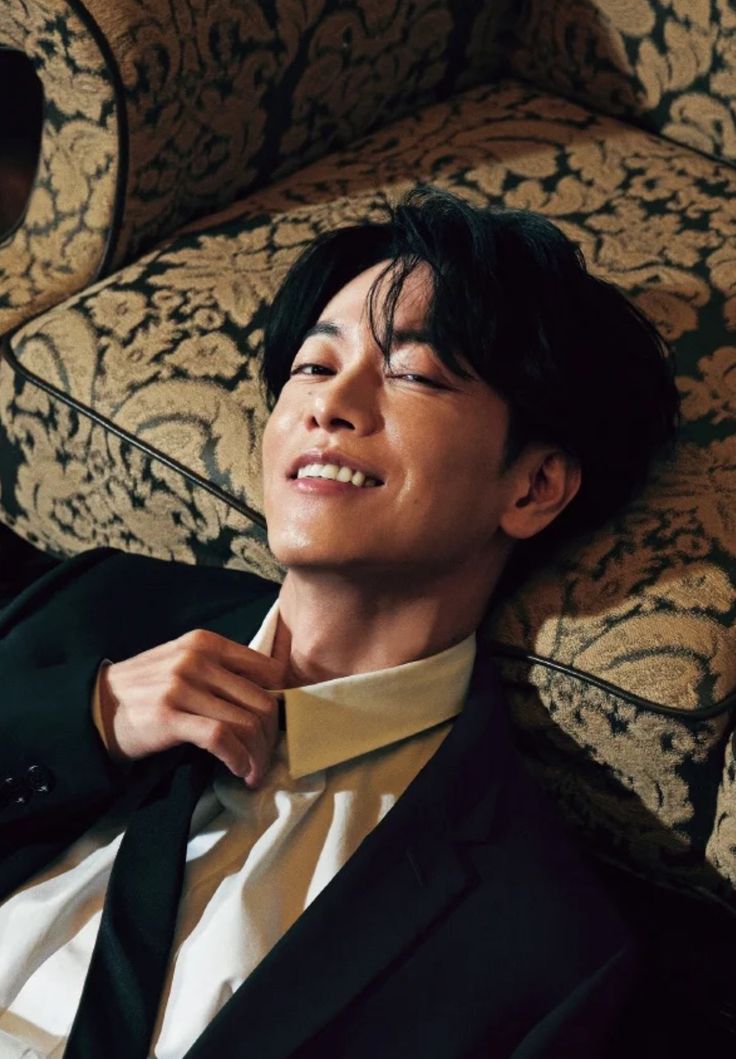 a young man laying on top of a chair wearing a suit and bow tie with his eyes closed