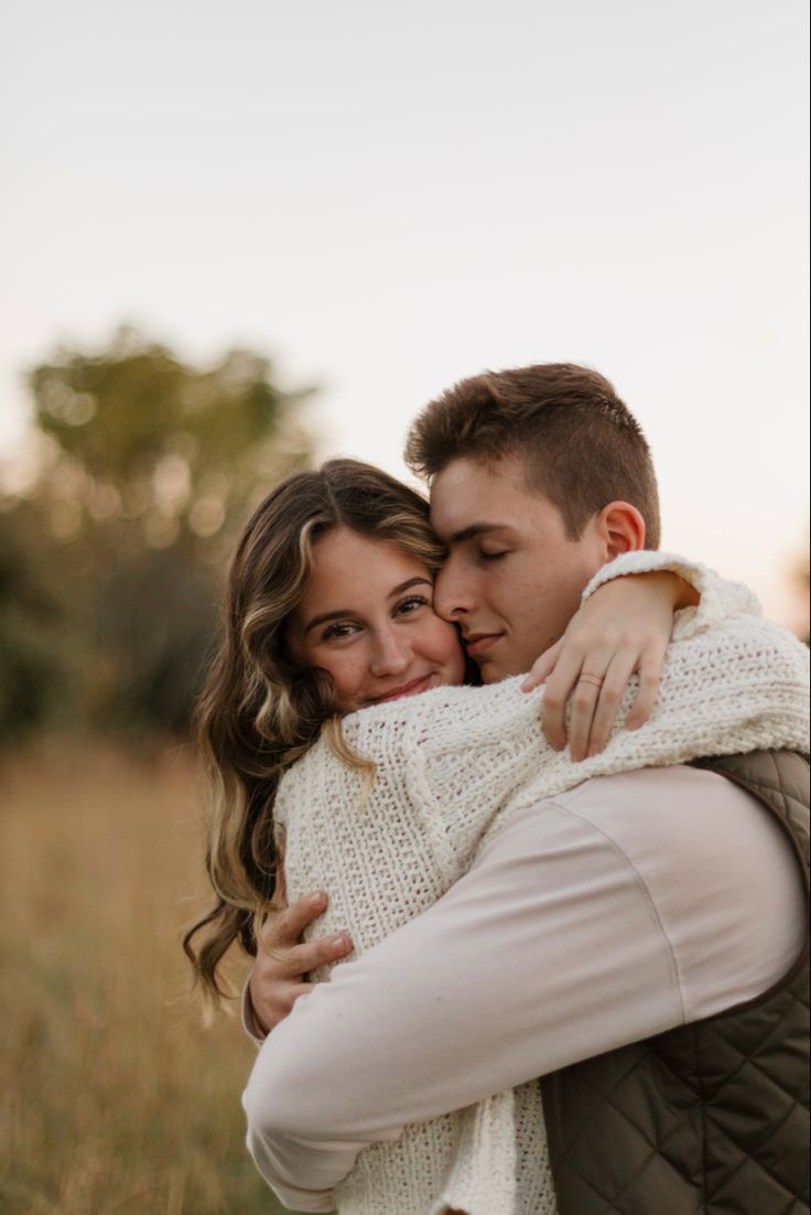 a man and woman hugging each other in a field