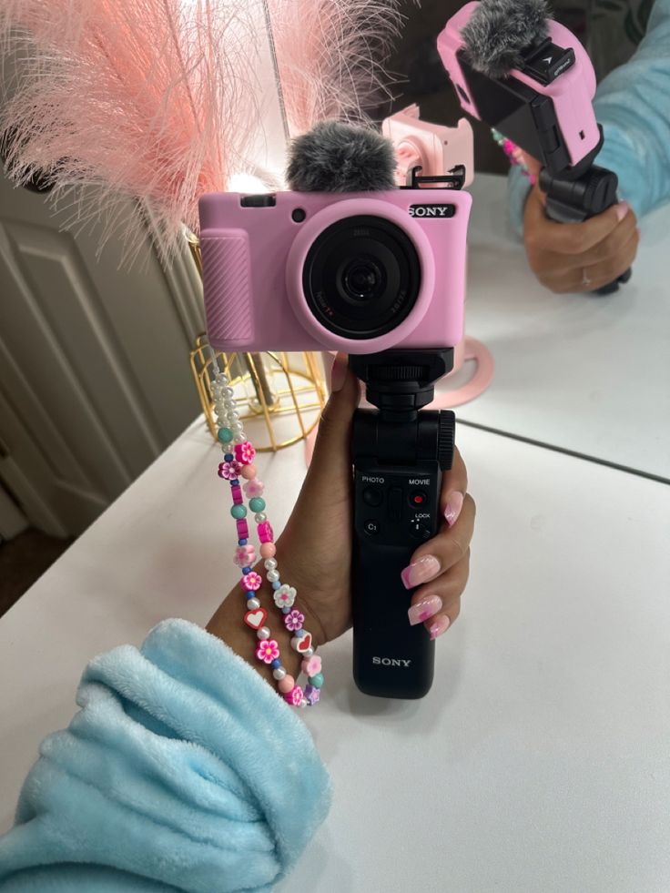 a person holding up a pink camera