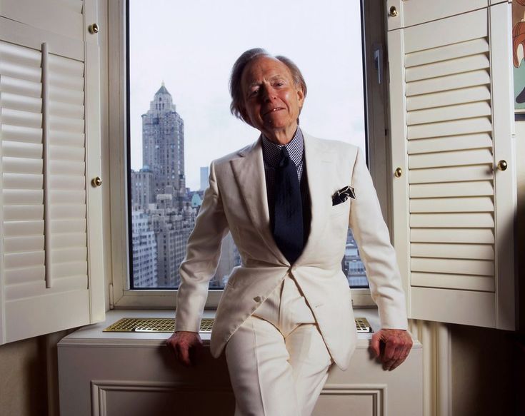 an old man in a white suit and tie leaning on a window sill looking out the window