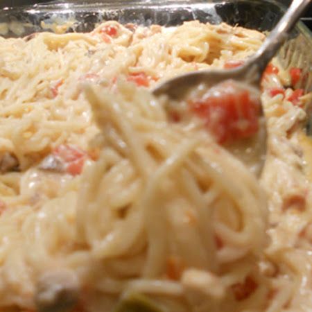 a spoon full of pasta and sauce in a casserole dish