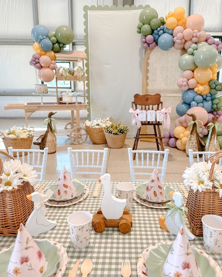 a table set for a tea party with balloons and flowers in the background, along with other decorations