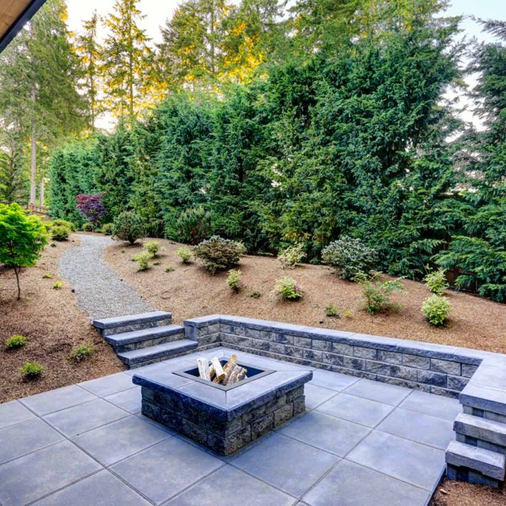 an outdoor fire pit surrounded by trees and shrubs with the words our backyard large landscape tricks