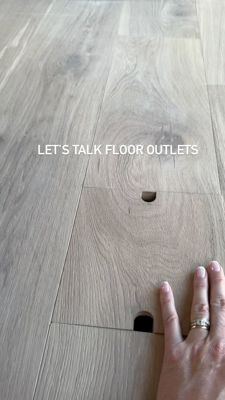 a hand is pointing at a hole in the floor that says, let's talk floor outlets