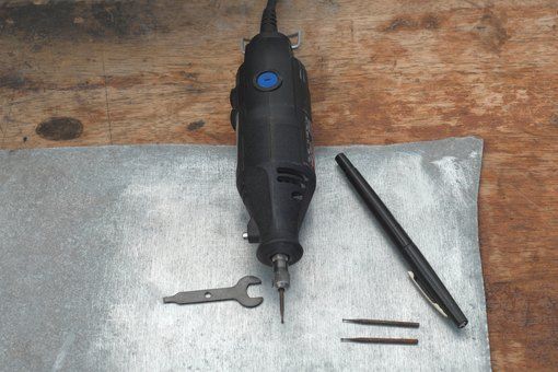 a cordless electric drill and some tools on a piece of cloth next to a pair of screwdrivers