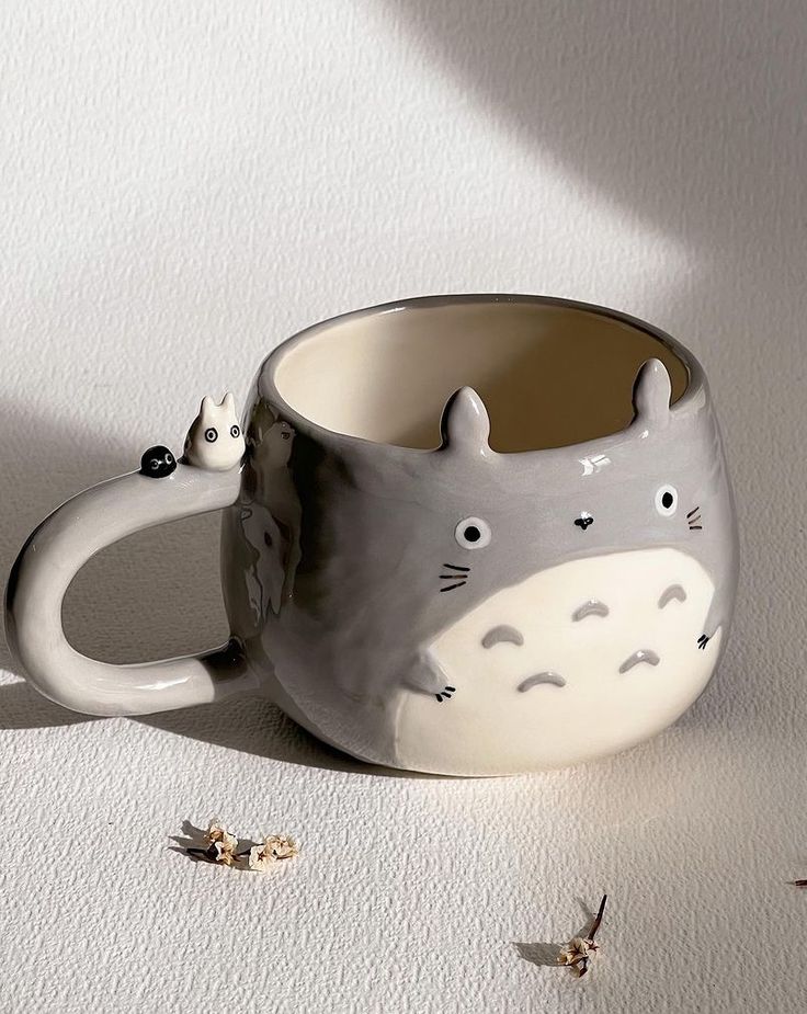 a ceramic mug with a totoro design on the inside and two tiny birds flying around it