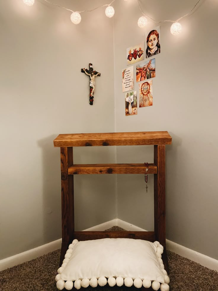 a small wooden table with a white pillow on it and some lights hanging from the ceiling