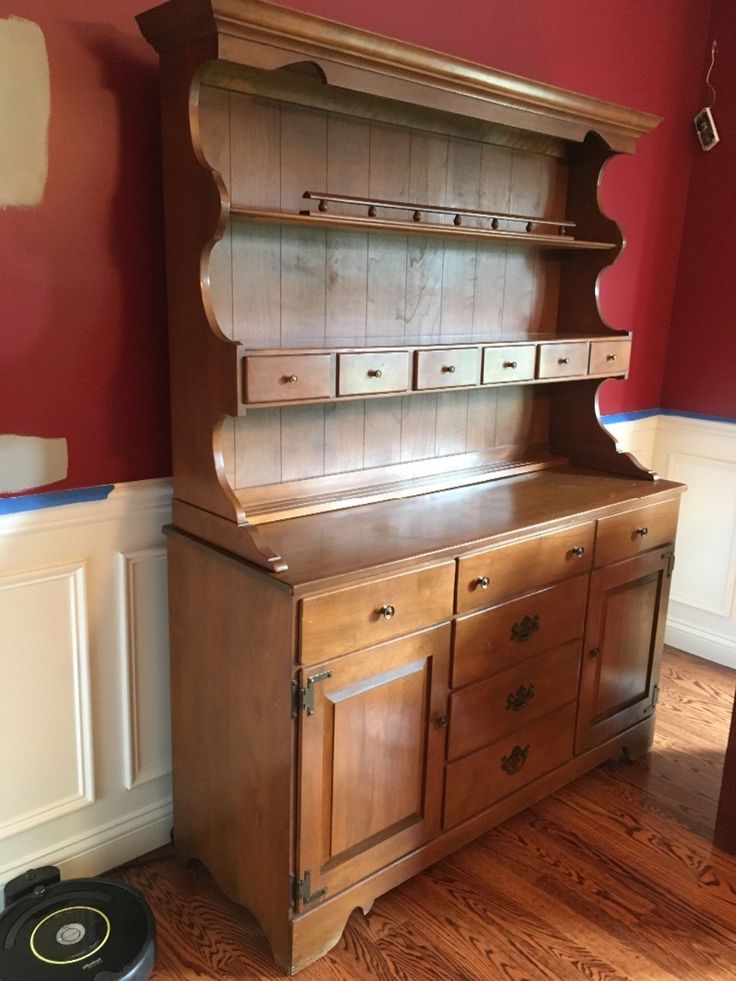 an old wooden cabinet with drawers in a room that has red walls and hardwood floors