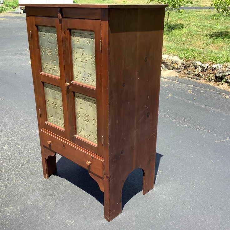 an old wooden cabinet sitting on the side of a road