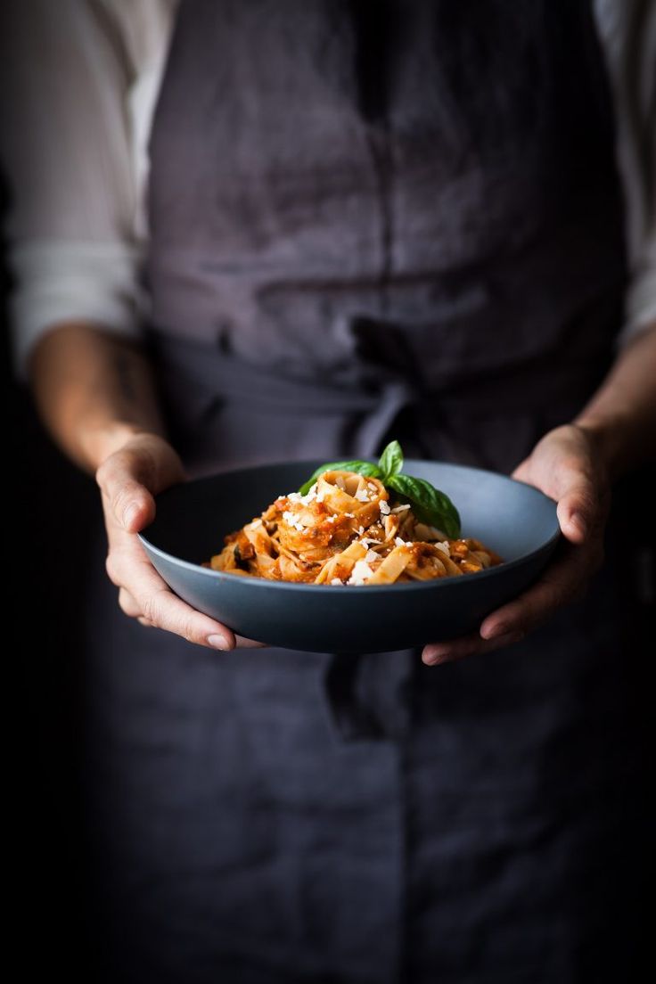 a person in an apron holding a bowl of food