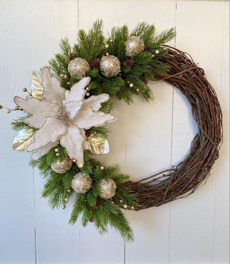 a christmas wreath hanging on the side of a white door with silver and gold decorations