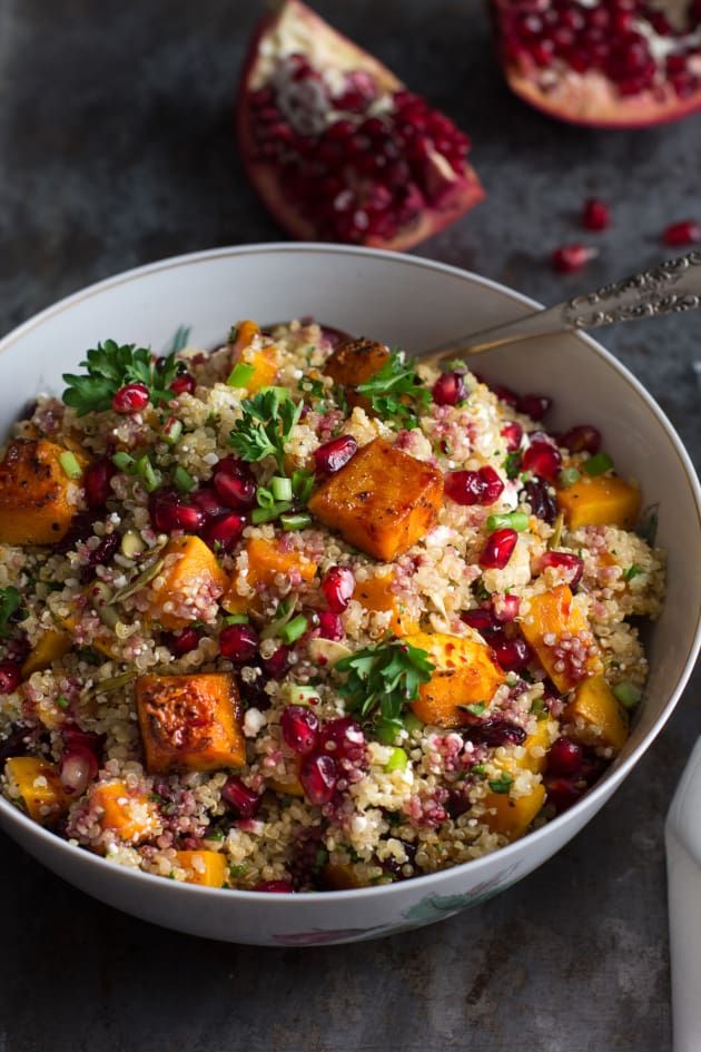 a white bowl filled with rice and pomegranate on top of a table