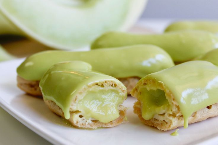 a white plate topped with pastries covered in green icing next to an apple