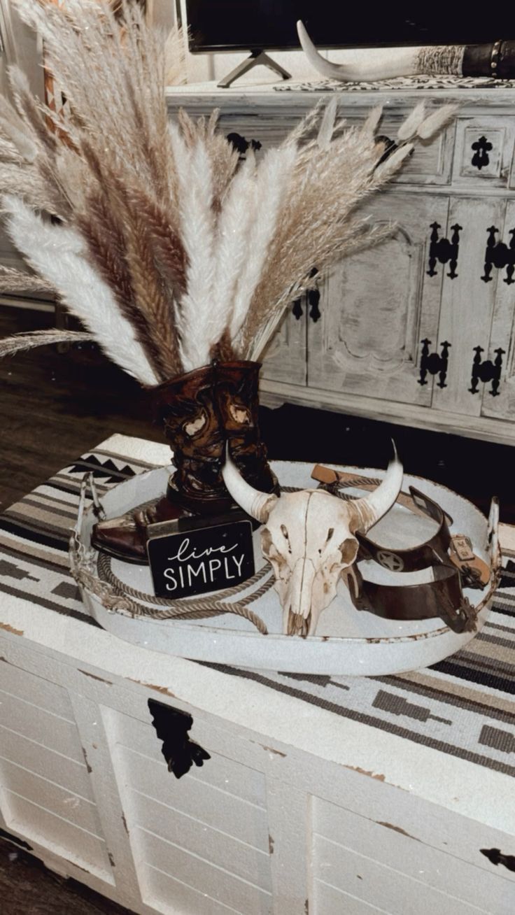 an animal skull with feathers on top of it sitting on a table next to other items