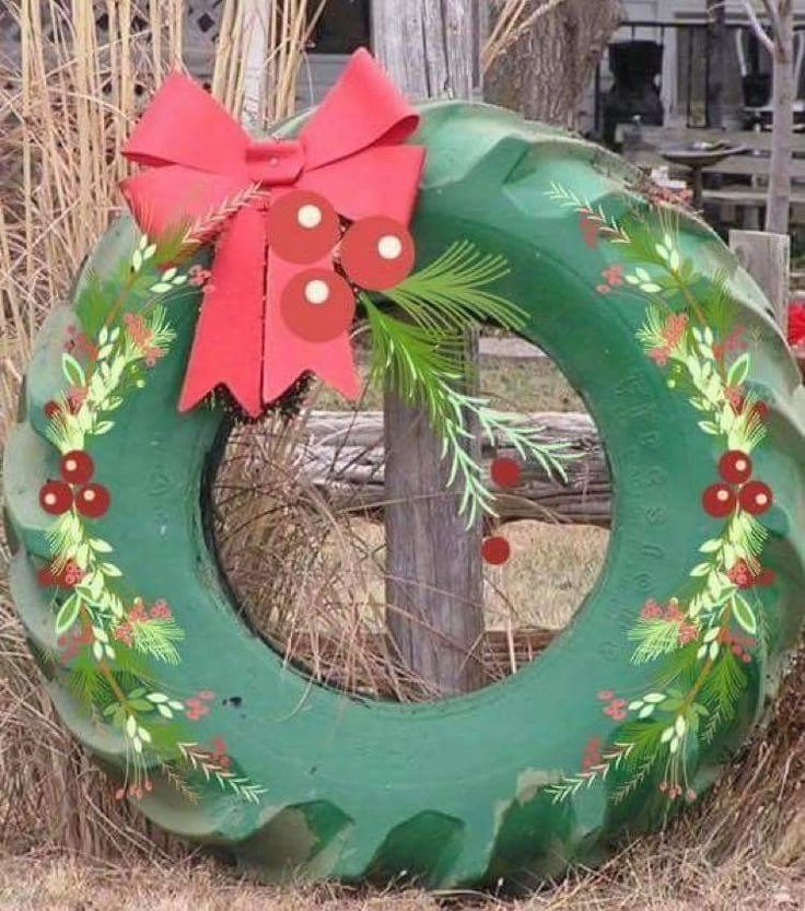 a green wreath with a red bow on it sitting in front of a wooden fence