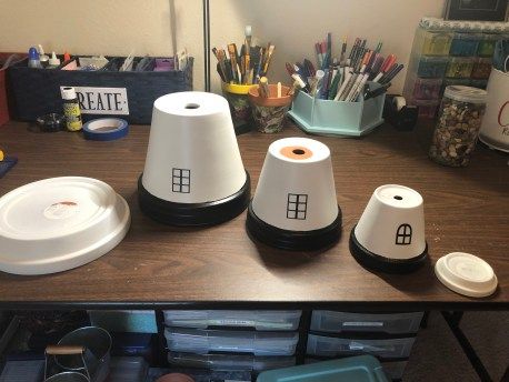 three white cups sitting on top of a wooden table next to other containers and utensils