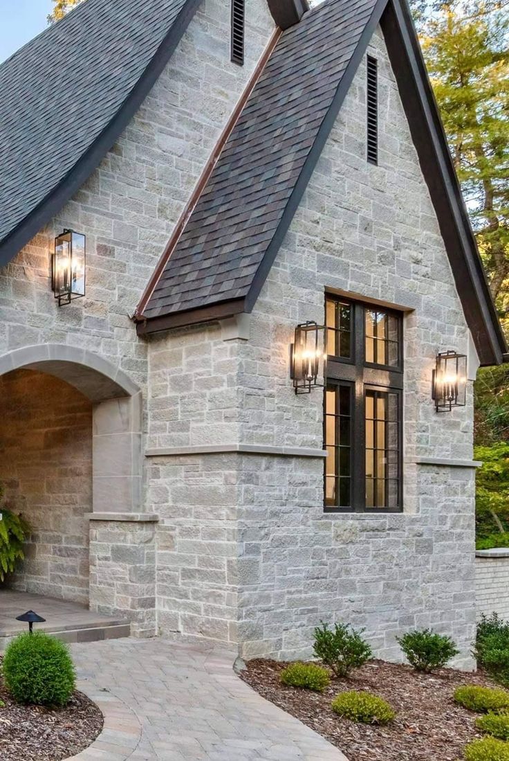 a stone house with two lights on the front door and windows in the side wall