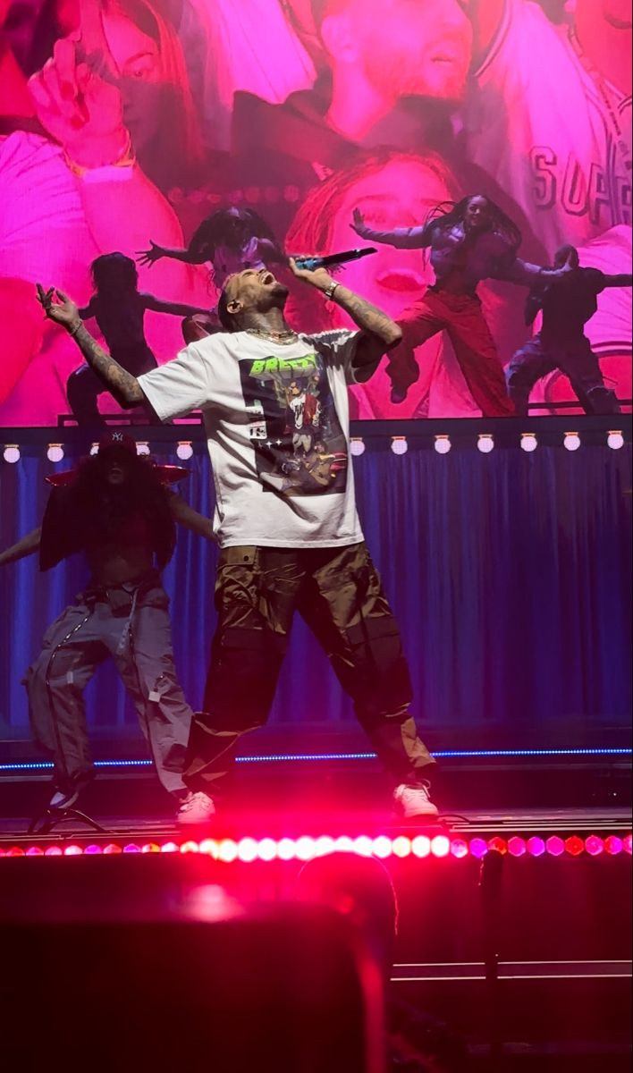 a man standing on top of a stage with his hands in the air