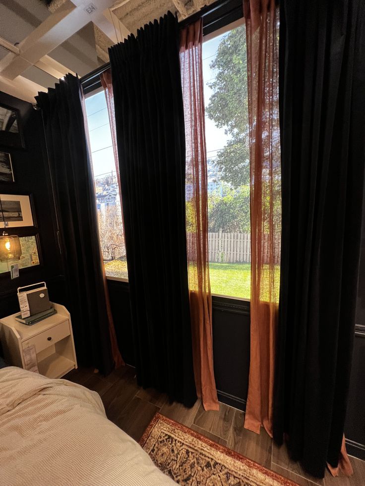 a bedroom with black curtains and a white bed