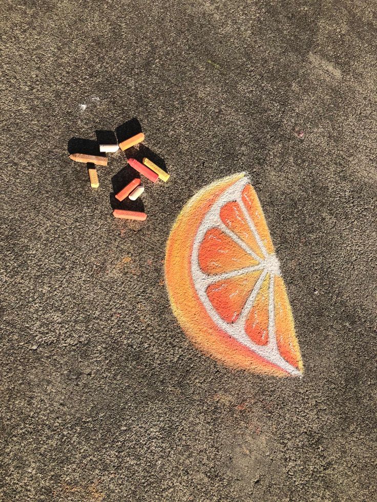 an orange and some crayons on the ground